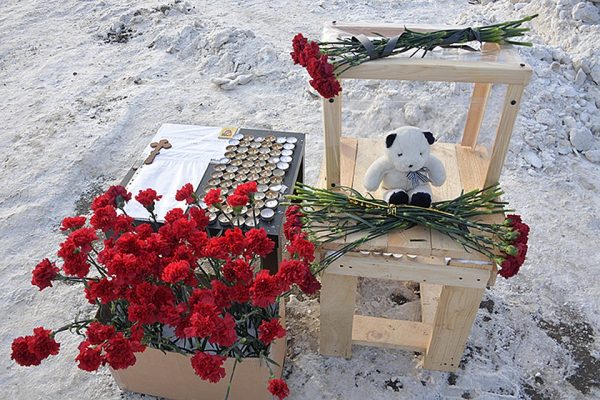 На место трагедии люди приносят много цветов