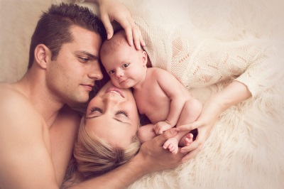 Мама и папа целуют новорожденного, любят его