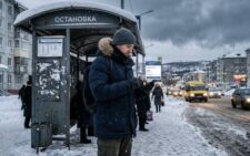 Человек в тёплой зимней одежде на остановке в Мурманске