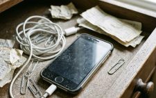 приоткрытый ящик письменного стола, внутри лежит старый смартфон с потертым корпусом