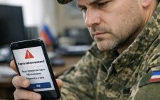 Военнослужащий в форме смотрит на экран смартфона с уведомлением о блокировке банковской карты